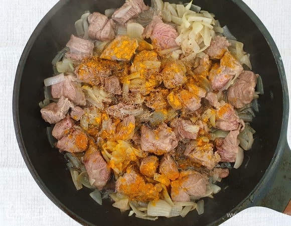 Добавим в мясо соль, перец, куркуму, зиру. Обжарим все вместе 2 минуты.