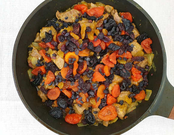 Добавим промытые сухофрукты. Если чернослив и курага крупные, разрежьте их на 2 части. Вольем еще одну столовую ложку масла и обжарим мясо с сухофруктами 2–3 минуты.