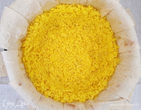 Выкладываем на лаваш половину риса. Слегка примнем рис таким образом, чтобы получилась чаша с бортиками. Во время запекания мясо и сухофрукты не должны касаться лаваша.