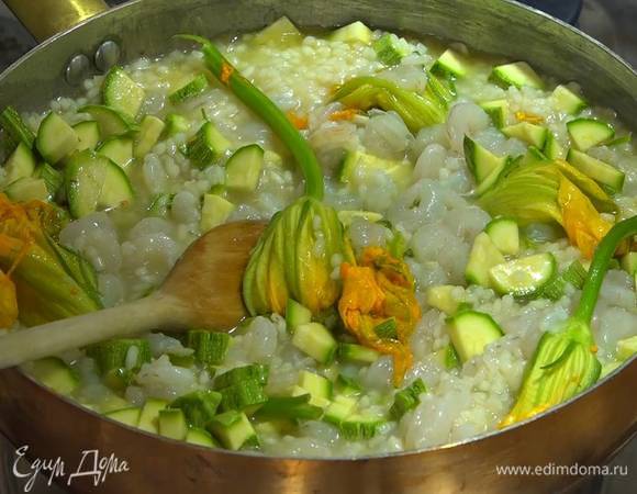 Цукини нарезать небольшими кусочками и выложить в ризотто вместе с цветками цукини и креветками, все перемешать, затем добавить оставшийся бульон, раскрошенный пальцами пеперончино, посолить, влить оставшееся вино, перемешать и довести до готовности.