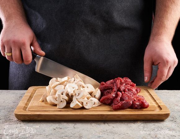 Говяжью вырезку нарежьте тонкими ломтиками длиной примерно 3–5 см. Шампиньоны разрежьте на кусочки.