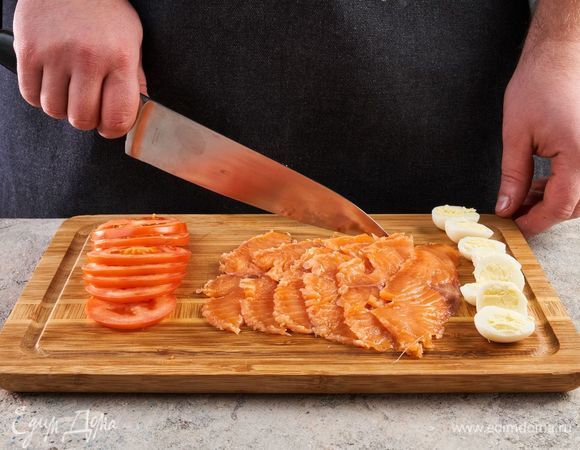 Перепелиные яйца отварите 3 минуты, разрежьте пополам. Помидор нарежьте кружочками. Форель нарежьте слайсами.