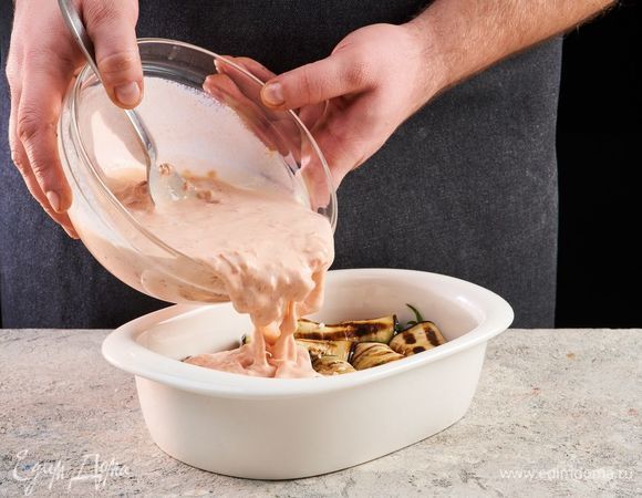 Выложите начинку на баклажаны и сверните рулетики. Выложите рулетики на противень, смазанный маслом. Залейте сливочно-томатным соусом. Выпекайте при 180°С в духовке 20 минут. 