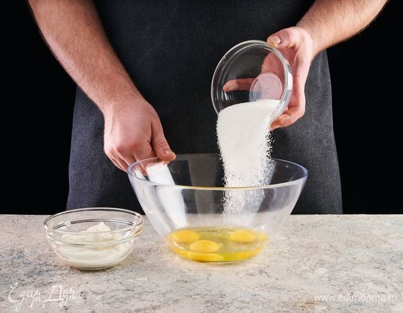 В большой чашке смешайте полстакана сахара, яйца и сметану.