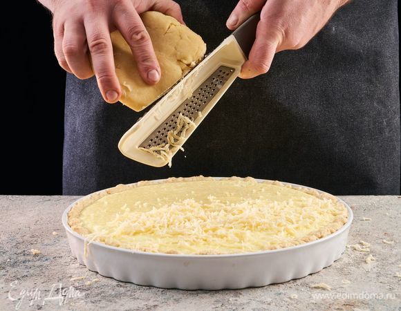 Замороженный кусок теста достаньте из морозильника. Натрите на ватрушку. Выпекайте еще 30 минут при 180°С.