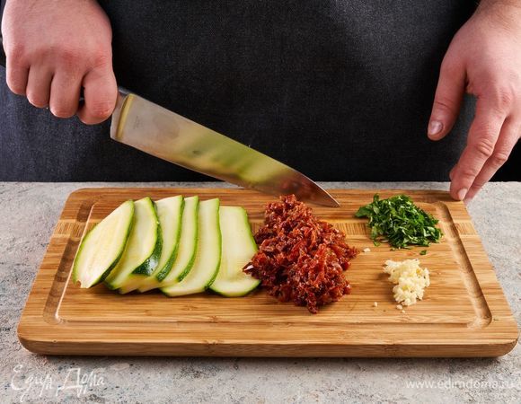 Разрежьте цукини вдоль тонкими пластинами. Чеснок почистите. Измельчите чеснок, кинзу и вяленые помидоры.