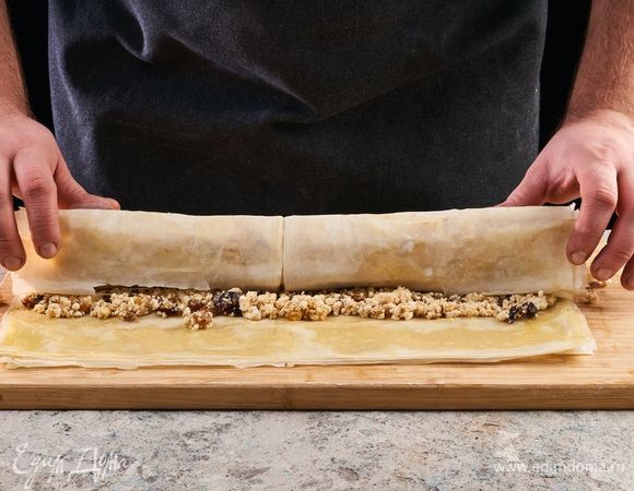 Выложите начинку. Сверните рулет и сверху смажьте растопленным сливочным маслом. Выложите рулет на противень, застеленный пекарской бумагой. Выпекайте при 180°С 35–40 минут.