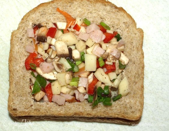 Кладем хлеб с вырезанной серединой на второй кусок. Накладываем начинку.