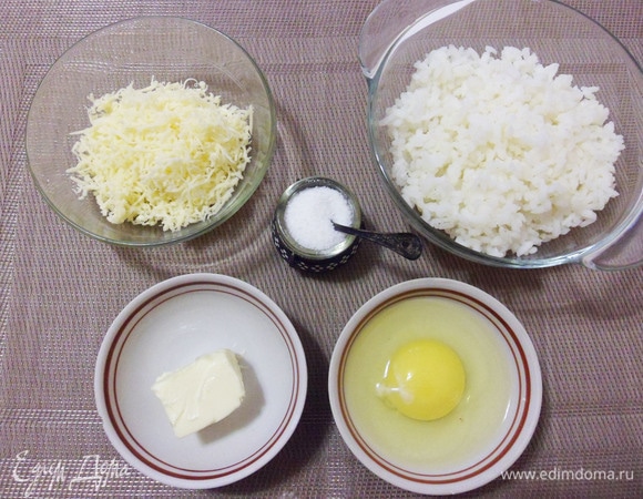 Рис тщательно промыть до прозрачности воды и отварить до полной готовности в подсоленной воде на медленном огне. Откинуть рис на дуршлаг и остудить до теплого состояния. Твердый сыр натереть на средней терке. Переложить рис в миску, вмешать сырое куриное яйцо, половину натертого сыра, половину сливочного масла и щепотку соли. Все хорошо перемешать. 