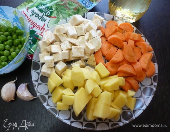 Подготовить овощи для запекания. Все вымыть и почистить. Нарезать кубиком. Чеснок нарезать пластинками. Горошек пока не трогать.