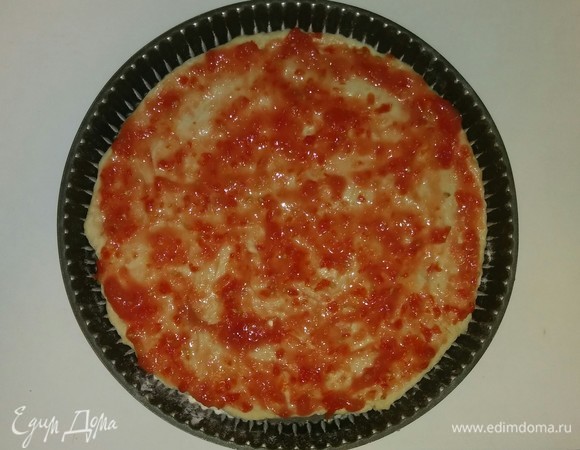 Смазываем форму для выпечки оливковым маслом и посыпаем чуть-чуть мукой. Раскатываем тесто по форме и смазываем соусом.