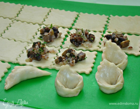 Тесто раскатать в тонкий пласт, не подсыпая муки. Тесто само по себе очень пластичное и не липнет. Нарезать на квадраты размером 5х5 см, положить на каждый квадрат немного начинки и сформовать пельмени в виде ушек.