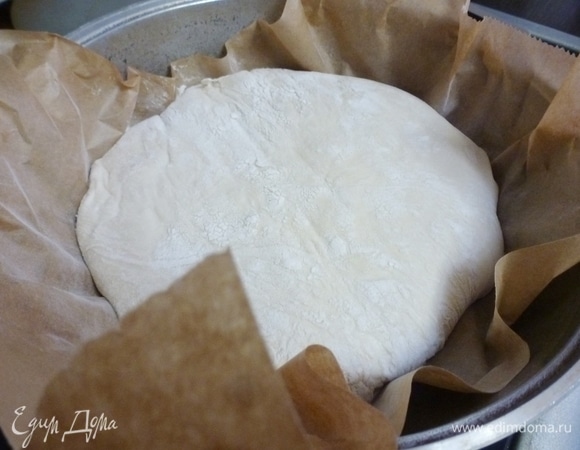 За полчаса до выпечки хлеба включить духовку на 250°C. Поставить туда чугунную или другую толстостенную кастрюлю, а можно казан с крышкой. Крышка должна быть без пластмассовой ручки. Кастрюля должна хорошо нагреться. У меня приспособлена глубокая сковорода. Через полчаса вытащить емкость и аккуратно поместить внутрь будущий хлеб вместе с бумагой. Бумага должна быть надлежащего качества и выдерживать высокие температуры.