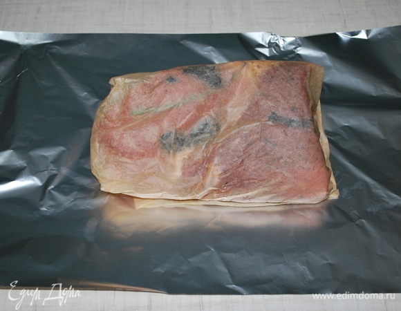 Заверните мясо в пергаментную бумагу, а потом в фольгу. Поставьте запекаться в духовку на 1,5 часа при температуре 180°C до готовности.
