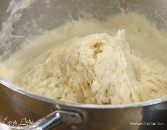 Просеять 1 кг муки в чашу комбайна, добавить предварительно размягченное сливочное масло и растереть все руками, затем всыпать сахар, соль, дрожжи и вымешать насадкой-крюком на небольшой скорости. Не выключая комбайна, влить небольшими порциями 650 мл теплой воды и вымешивать тесто еще 5 минут.