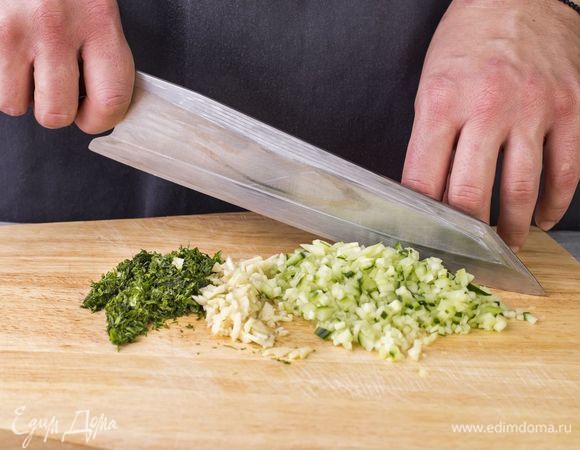 Приготовьте соус. Мяту и укроп мелко порубите. Чеснок выдавите через пресс. Очистите и измельчите огурцы. Лишнюю жидкость отожмите.