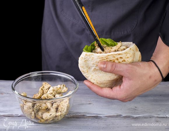 В питу положите салатный лист, кольца красного лука, помидоры и обжаренные кусочки курицы.