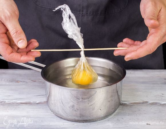 Сварите яйцо пашот. Для этого пищевую пленку выложите на пиалу, а в углубление выложите яйцо. Соберите концы пленки в узелок, закрепите длинной шпажкой, чтобы удобнее было вытаскивать из кастрюли. Опустите в кипящую воду на 5–7 минут. 