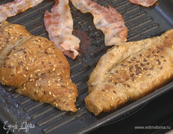 Круассан разрезать пополам, поджарить с двух сторон на той же сковороде, где жарился бекон.