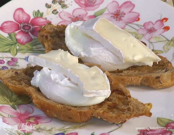 На тарелки выложить половинки круассана, сверху — яйцо, на него сыр бри и бекон.