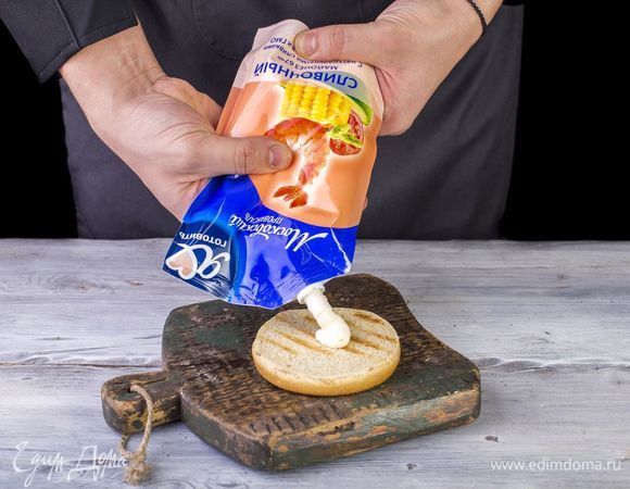 Осталось собрать бургер. Нижнюю часть булки полейте майонезом Сливочный ТМ «Московский провансаль» («Я люблю готовить»).