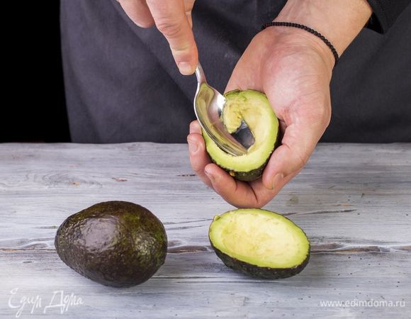 Авокадо разрежьте пополам и вытащите косточку. Удалите немного мякоти авокадо. Сыр натрите на крупной терке.
