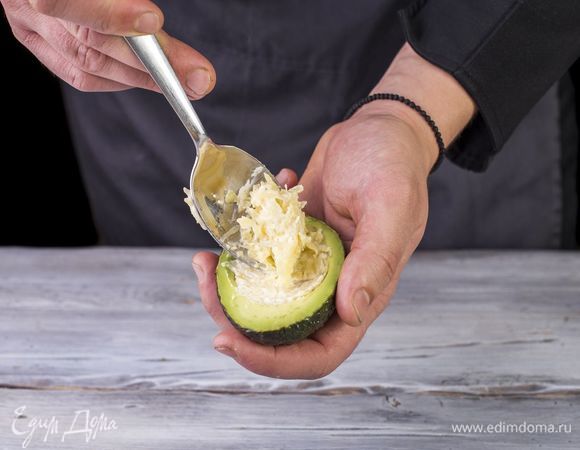 Выложите получившуюся начинку на половинки авокадо и натертый на крупной терке сыр.