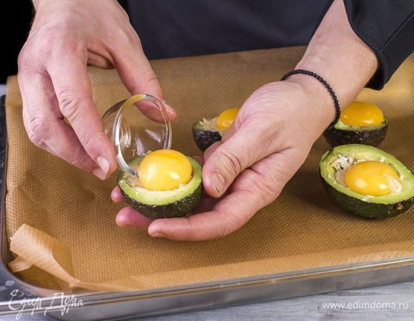 Сверху в каждую половинку разбейте по одному желтку. Посолите и поперчите. Запекайте в духовке 10 минут при 200°С.