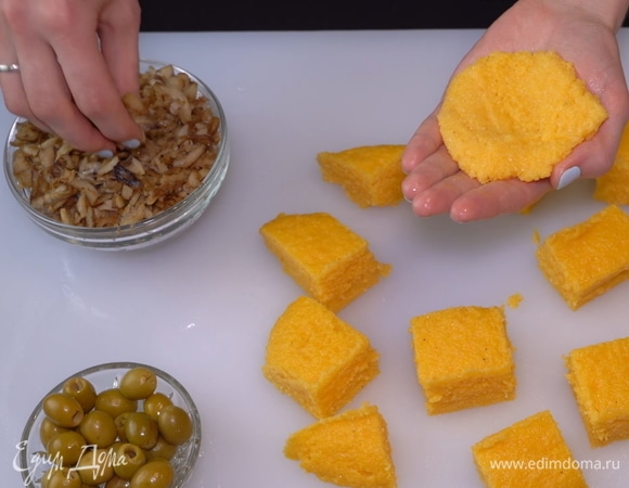 Смачиваем руки в воде и берем немного мамалыги. Перебрасываем ее с ладони на ладонь, чтобы сделать более плотной. Расплющиваем шарик из мамалыги в тонкий блинчик.