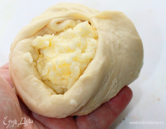 Каждую из пяти порций теста слегка посыпать мукой и скалкой раскатать в круг толщиной 5 мм. По периметру сделать проколы зубочисткой, деревянной шпажкой или кончиком ножа, чтобы выпустить воздух. Выложить в центр каждого круга 150 г сырной начинки — смеси имеретинского сыра, сулугуни (70 г пока оставить) и обычного яйца. Соединить края теста и защипнуть. Чуть посыпать пироги мукой, снова раскатать их скалкой до диаметра формы для выпечки и толщины 8–10 мм.