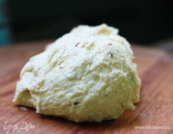 Подготовим опару. В чашку налить теплую воду, добавить сахар и перемешать до растворения сахара. Всыпать дрожжи, накрыть и оставить на 15 минут. Розмарин и тмин, если свежие, нарезать. Сыр натереть на терке. В большую миску просеять муку, соль, добавить натертый сыр и травы. Все перемешать. Влить дрожжи с водой, перемешать. Добавить яйцо и замесить тесто. Чтобы тесто было легче замесить, добавляем 2 столовые ложки оливкового масла.