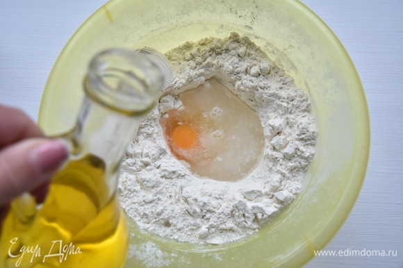 Для приготовления теста просеять муку в миску подходящего размера. В центре сделать углубление и влить теплую воду, добавить соль, яйцо, затем влить подсолнечное масло.