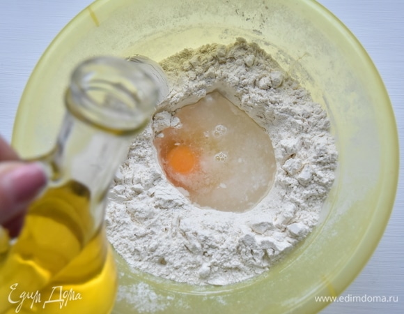 Для приготовления теста просеять муку в миску подходящего размера. В центре сделать углубление и влить теплую воду, добавить соль, яйцо, затем влить подсолнечное масло.