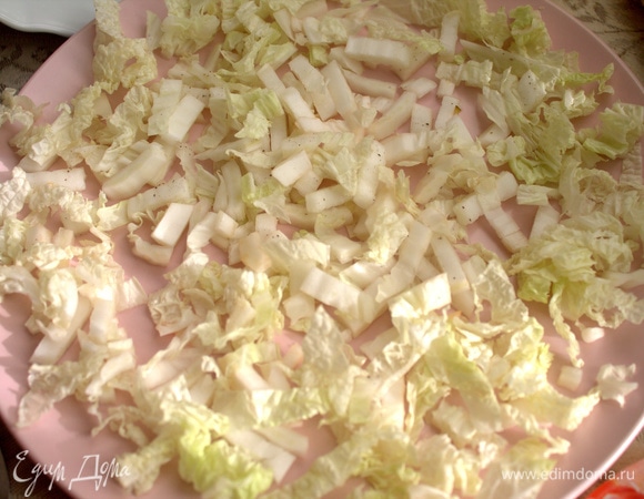 На плоскую тарелку выложить листья пекинской капусты, нарезанные небольшими кусочками.