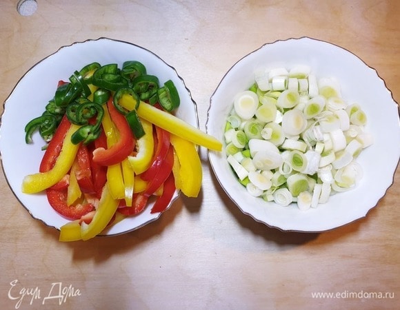 Полосками нарежем болгарский перец, перец чили — кольцами, белую часть зеленого лука нарежем колечками.