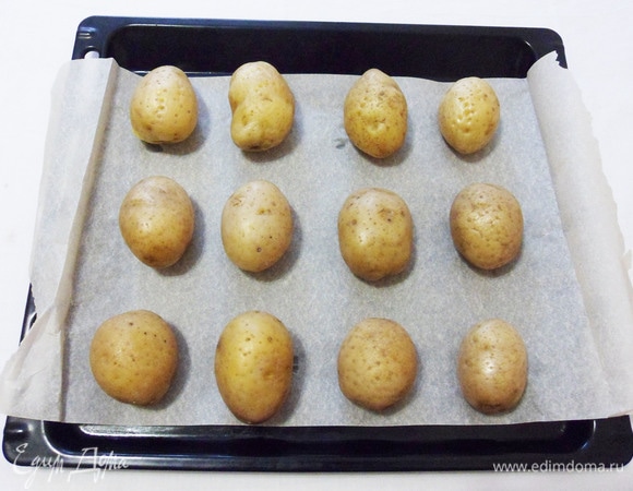 Выкладываем картошку на противень, застеленный пекарской бумагой, на расстоянии друг от друга.