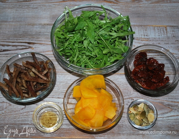 Горсть тыквенных семечек обжарьте, вяленые помидоры нарежьте. Руколу вымойте.