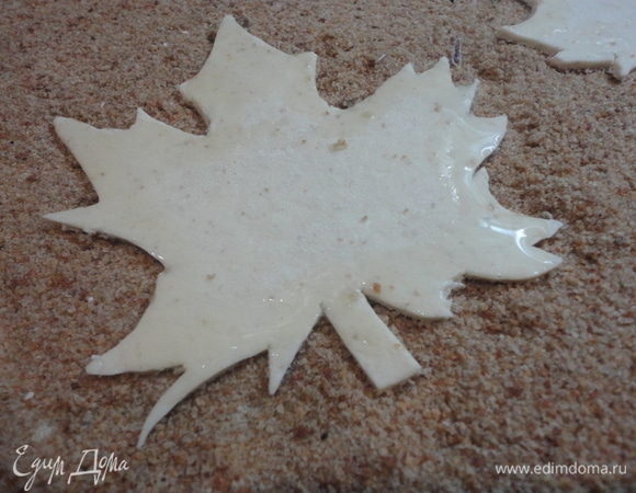 Из теста вырезаем листья. Лишнее тесто убрать. Края листьев смазать растительным маслом. Середину листьев смочить водой.