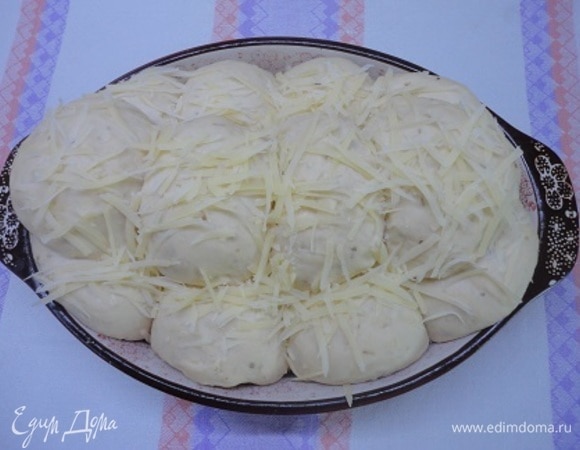 Подошедшее тесто обмять и разделить на 12 частей. Сформовать шарики и выложить в форму в два ряда по 4 штуки. Оставшиеся 4 шарика выложить сверху рядком. Оставить на 30 минут для расстойки посыпать оставшимся сыром.
