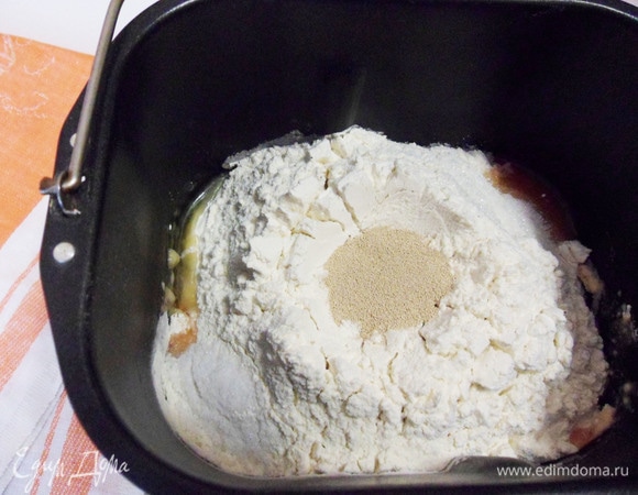 Загрузить в контейнер хлебопечки ингредиенты согласно инструкции. В моей хлебопечке сначала загружаются жидкие продукты. Поэтому наливаем в контейнер томатную воду, добавляем растительное масло, затем муку, соль, сахар и только потом в углубление в муке кладем дрожжи. Выбираем программу «Основная», вес — 900 грамм, корочка — светлая. Необходимо проконтролировать только процесс замеса колобка теста: если тесто жидкое (тянется за тестомесом), то необходимо добавить муку (по столовой ложке). Мне пришлось добавить еще 2 столовые ложки. Далее хлебопечка все сделает по программе.