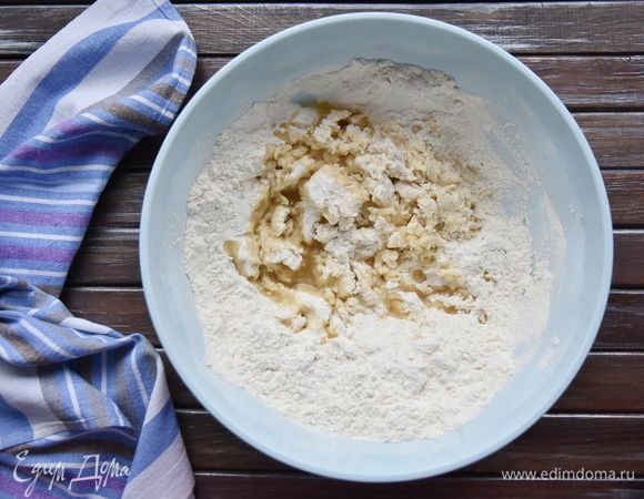 В миску с просеянной мукой ввести дрожжевую смесь и начать замешивать тесто. В процессе замеса влить подсолнечное масло.