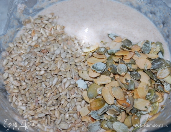 Добавьте семечки (оставьте немного семечек для посыпки булочек сверху). Постепенно, вымешивая, добавьте частями пшеничную муку (возможно, она понадобиться не вся).