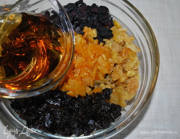 Подготовьте фрукты. Чернослив, финики и апельсиновые цукаты нарежьте. Залейте коньяком и перемешайте. Это надо сделать заранее. Чем дольше они будут настаиваться, тем лучше.