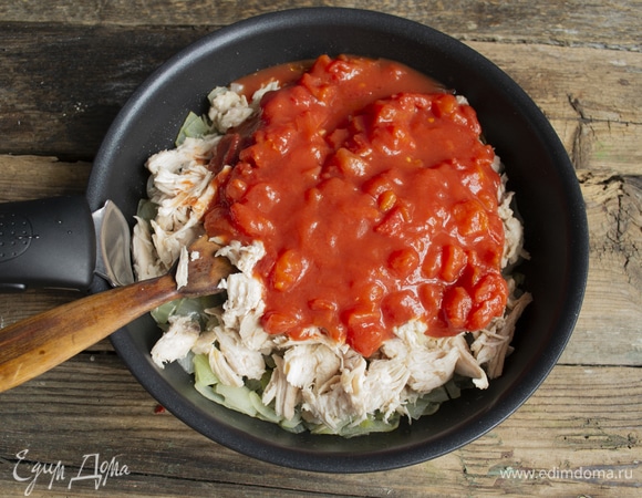 Теперь выкладываем в сковороду консервированные мелко нарезанные томаты вместе с соком. Перемешиваем, по вкусу солим, перчим, насыпаем молотую сладкую паприку. На сильном огне доводим до кипения, готовим 5 минут. Для баланса кислого и соленого можно добавить половину чайной ложки тростникового сахара.