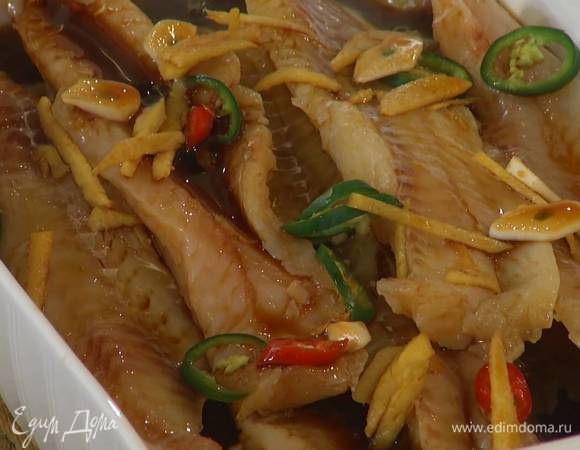 Филе минтая выложить в жаропрочную форму, посыпать нарезанным чили, залить горячим имбирно-соевым соусом и затянуть пищевой фольгой.