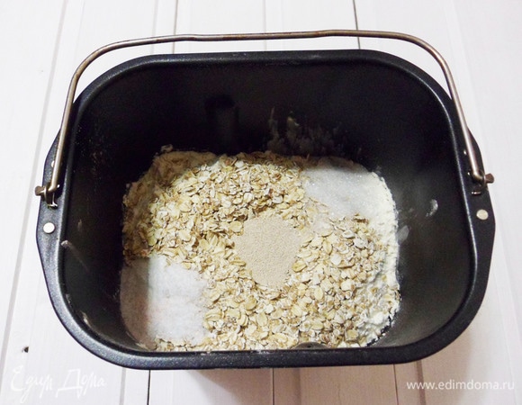 В емкость хлебопечки наливаем воду, добавляем оливковое масло, просеянную (взвешенную на весах) муку, хлопья, соль, сахар и сухие дрожжи. Устанавливаем емкость в хлебопечку. Выбираем режим «Французская булка», вес — 750 г, корочка — светлая. Старт. Через несколько минут необходимо проконтролировать замес. Если тесто тянется за тестомесом, то необходимо добавить муку. Муку следует добавлять постепенно, по одной столовой ложке. Если же, наоборот, тесто не собралось в колобок, необходимо добавить воду, тоже по одной столовой ложке. Дальше хлебопечка все сделает сама.