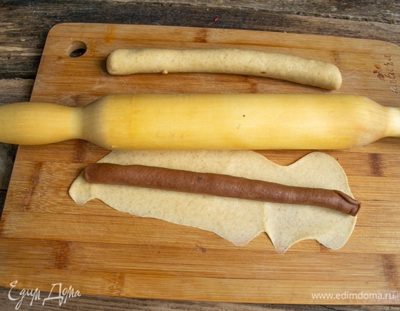 Раскатываем кусочек шоколадного теста, кладем на него колбаску из теста с корицей, заворачиваем, затем оборачиваем сверток тонко раскатанным светлым тестом.