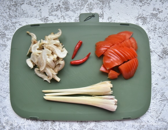 Лемонграсс раздавить и нарезать на сегменты по 4–5 см. С лайма снять цедру и выжать сок. Помидоры нарезать дольками, грибы — смоломкой. Перец чили разрезать вдоль пополам и удалить семена, корень галангала нарезать кружочками.