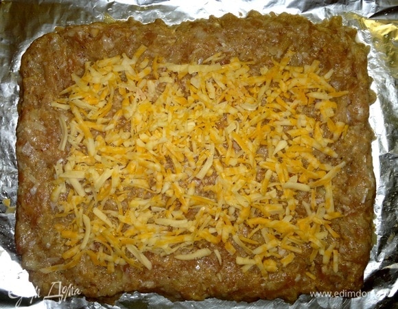 Сыр натереть на крупной терке. Часть сыра выложить на фарш, не доходя до краев 3–4 см.