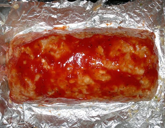 Соединить противоположные края фарша и сформовать рулет. Смазать рулет томатной пастой. Форму затянуть фольгой. Поставить форму с рулетом в духовку и запекать при 190–200°C 20–25 минут. За 5–7 минут до готовности открыть фольгу, чтобы рулет подрумянился.
